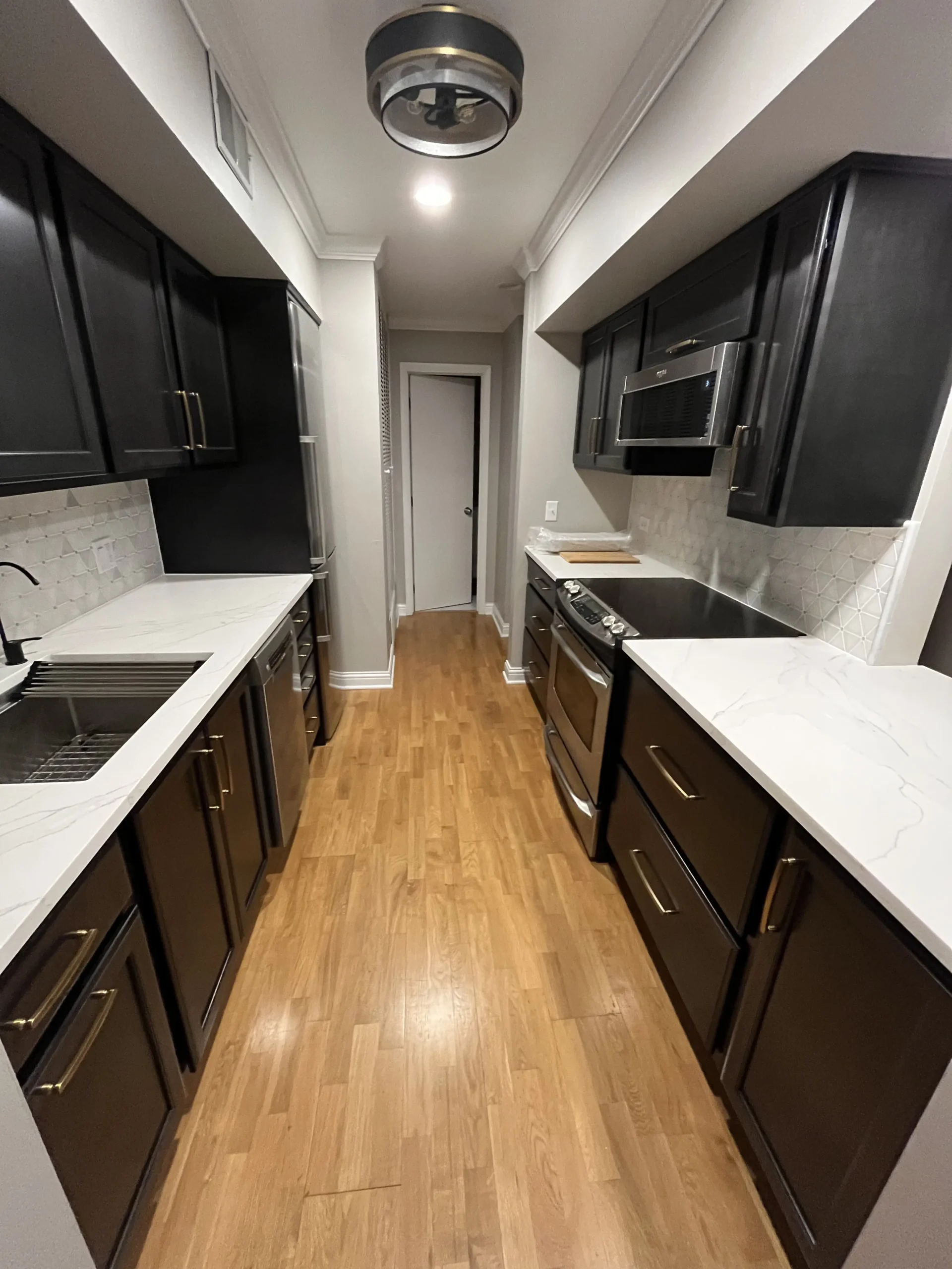 REIJ custom galley kitchen — espresso cabinetry, quartz counters, light oak floor